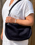 woman wearing a white shirt with a navy bag over their shoulder 