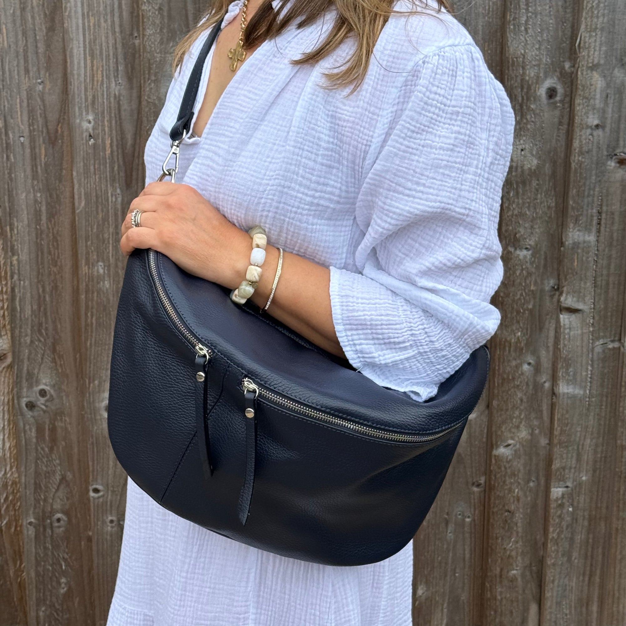 woman wearing a white dress holding a navy blue handbag against a wooden background