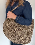woman holding a leopard print tote bag 