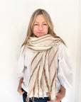 Woman wearing a white shirt and a pastel striped scarf.