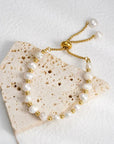 Pearl and gold bracelet on a textured stone surface