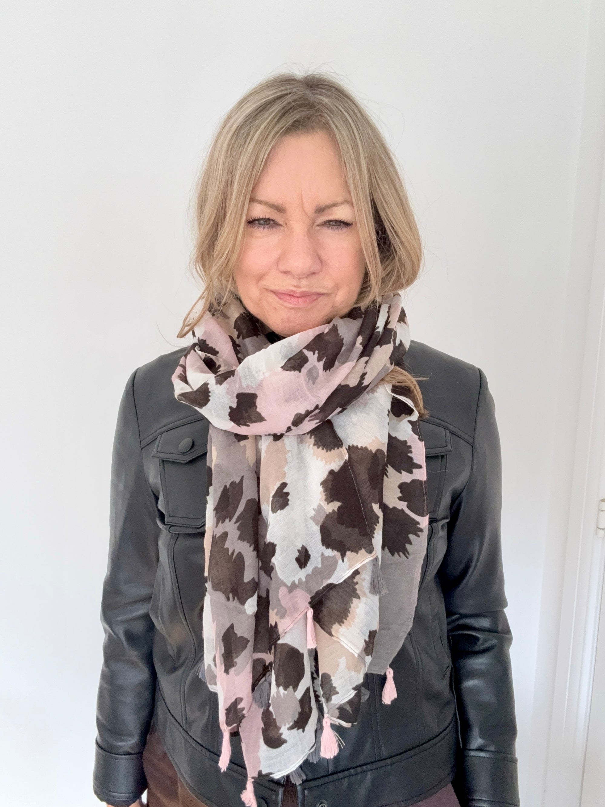 Woman wearing a patterned scarf and leather jacket against a white background