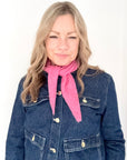 Woman wearing a blue denim jacket and pink scarf against a white background
