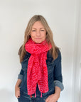 woman wearing a red and pink patterned scarf with a denim outfit
