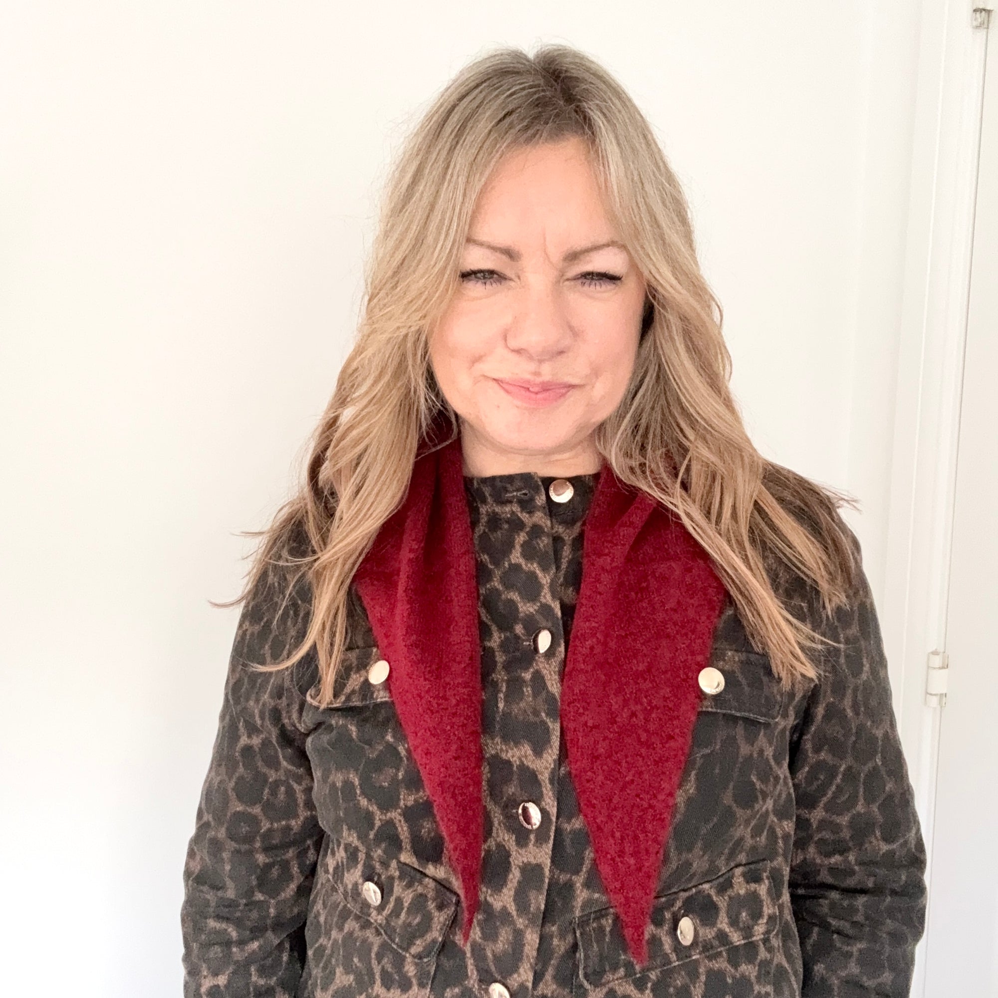 Woman wearing a leopard print coat with a dark red scarf 