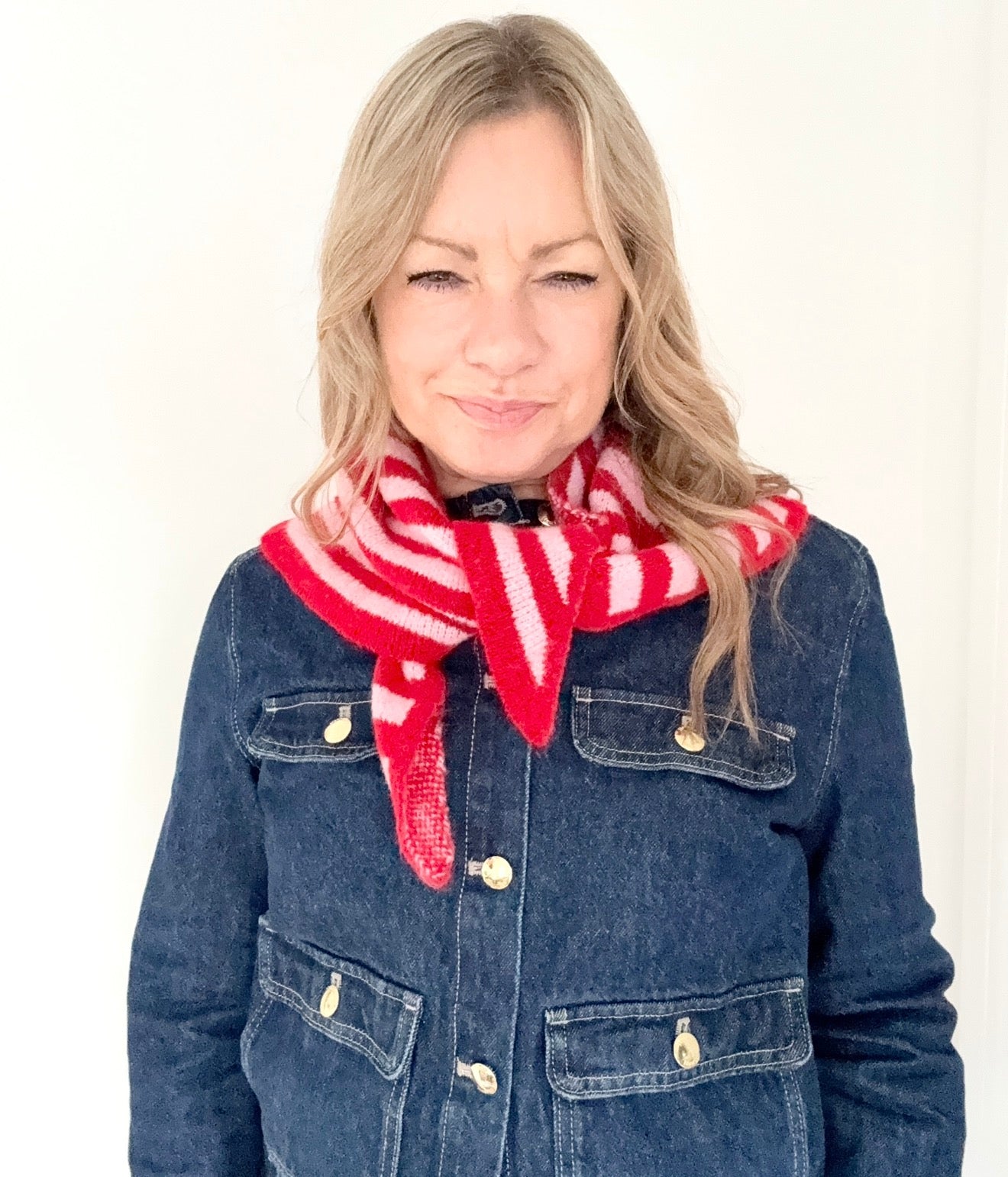 Woman wearing a blue denim jacket and red and pink striped knitted scarf 