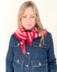 Woman wearing a blue denim jacket and red and pink striped knitted scarf 