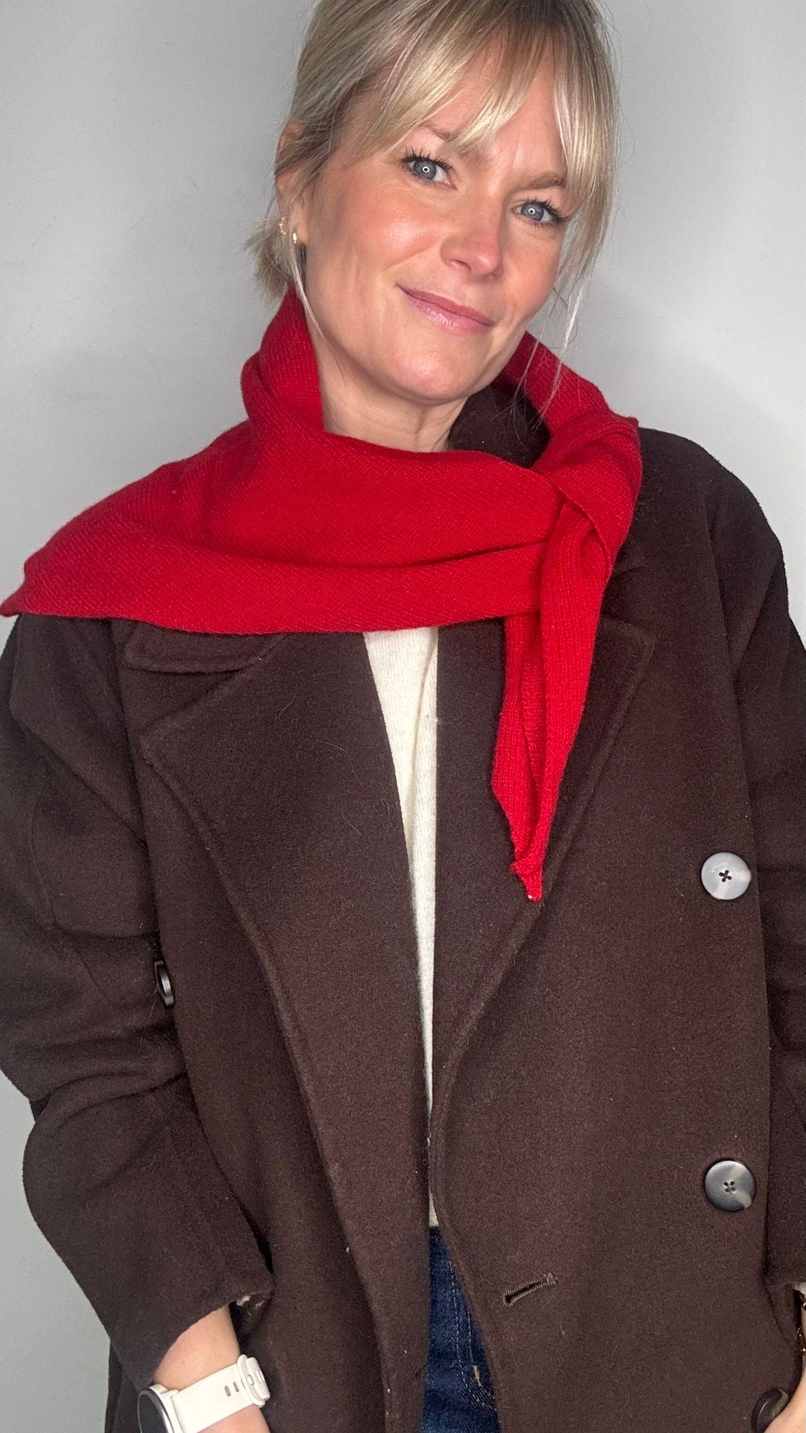 woman wearing a brown jacket and a red wool scarf
