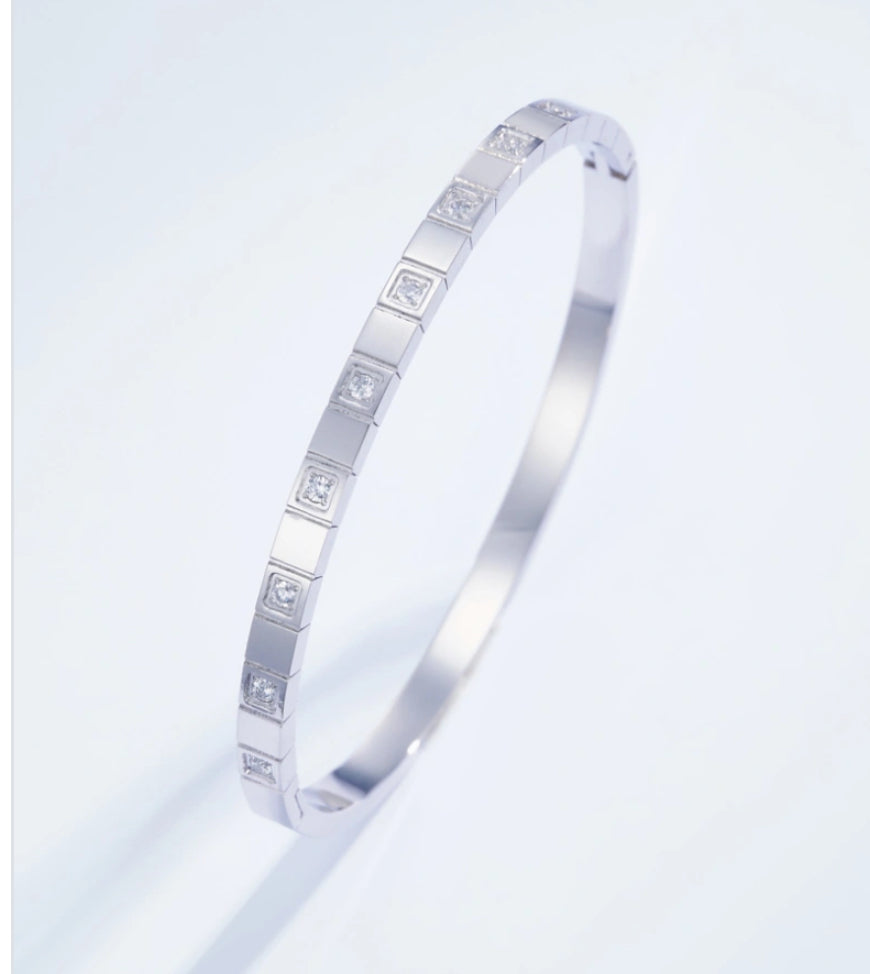 Silver bracelet with embedded diamonds on a light gray background