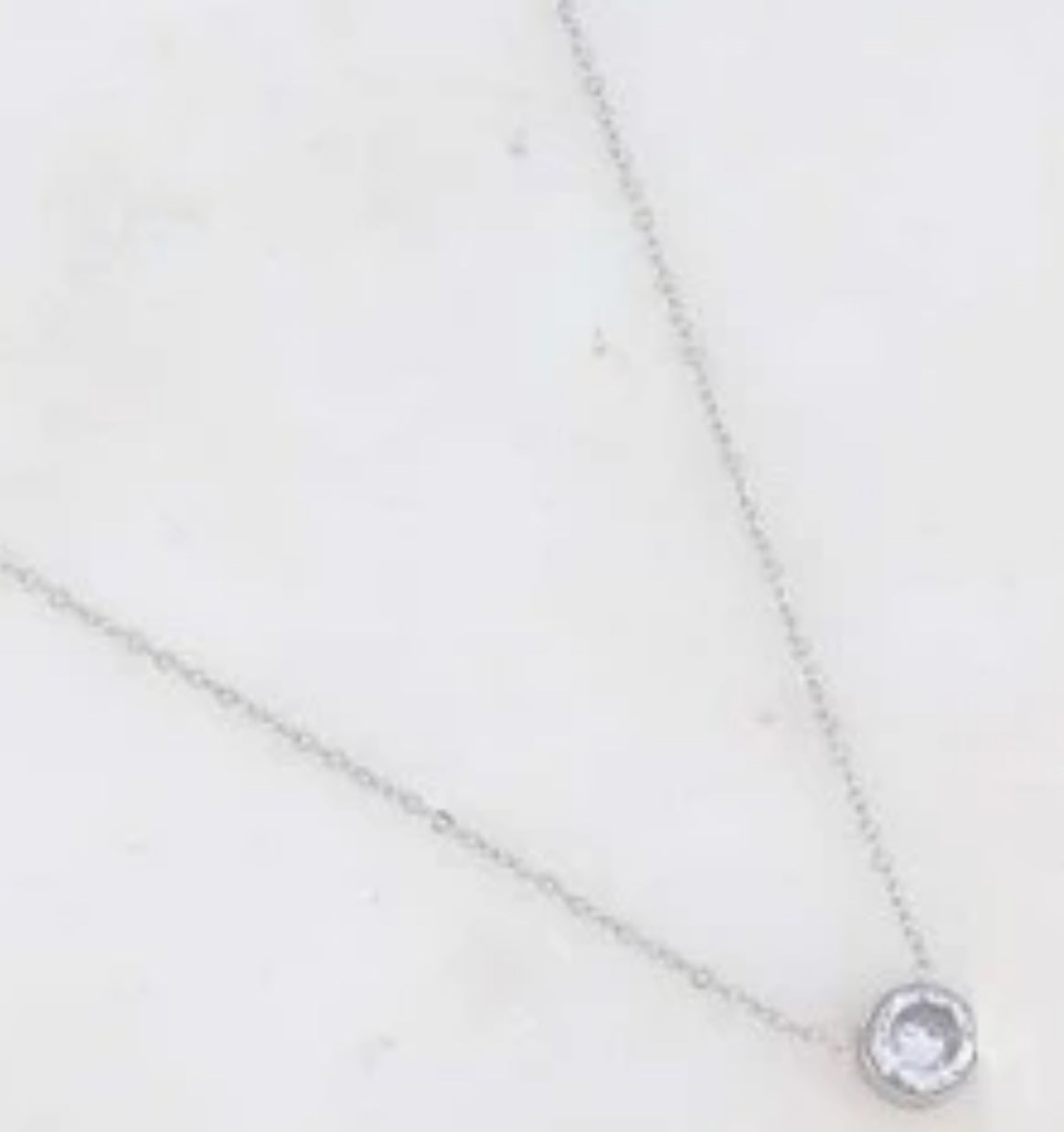 Silver necklace with a clear pendant on a light gray background
