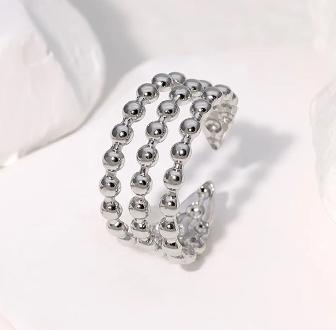 A silver-colored adjustable ring with a dotted pattern,  against a white background.