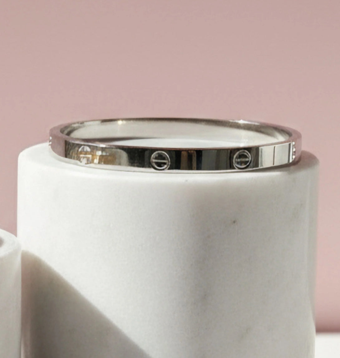 Silver bracelet on a white marble surface. 