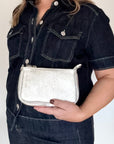 Woman holding a silver glittery leather clutch/ crossbody handbag. 