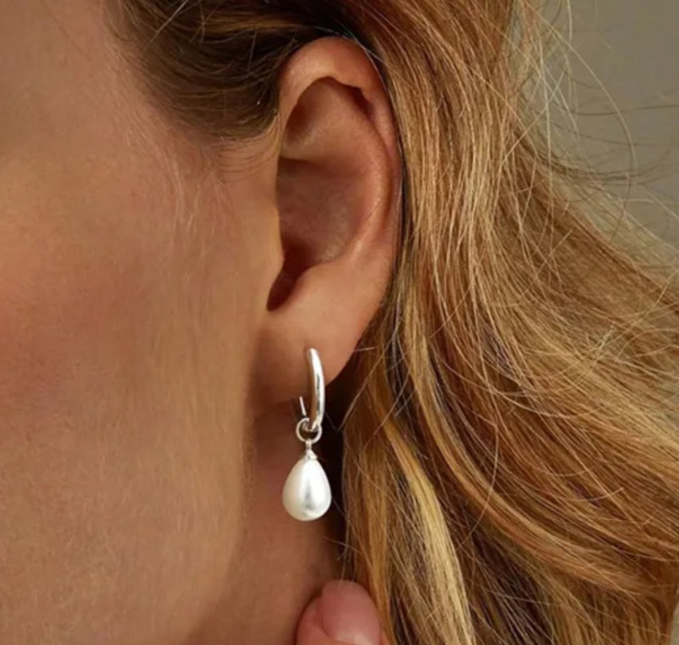 Close-up of a person wearing a pearl earring with blonde hair.