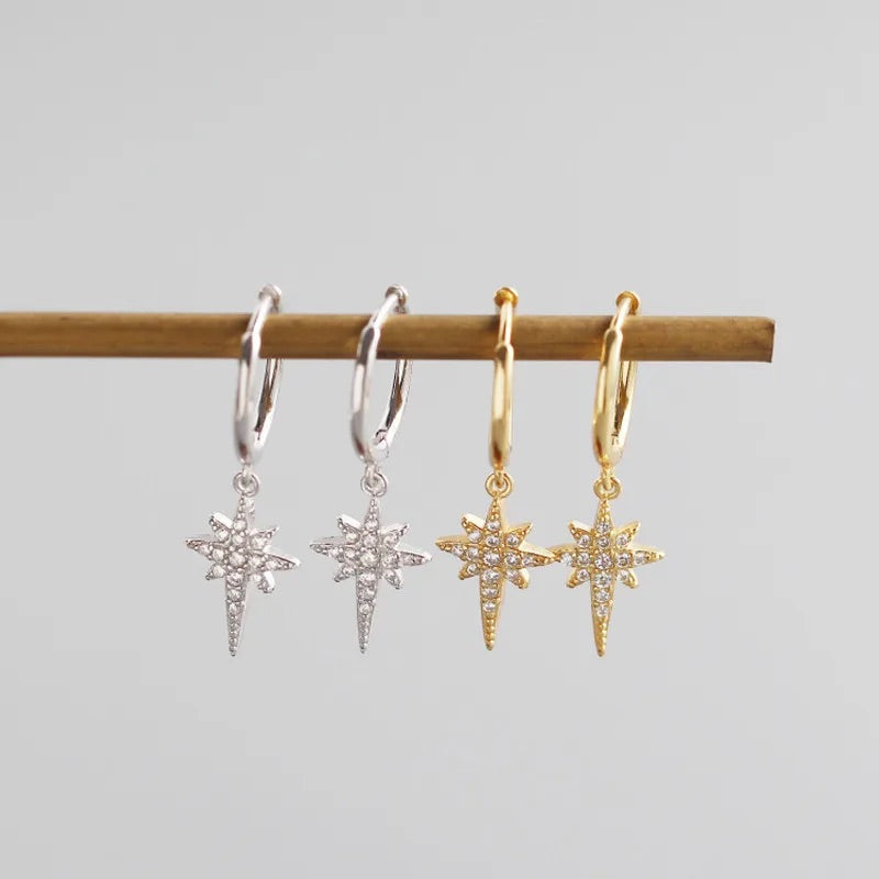 two pairs of silver and gold sparkly star hoop earrings. 
