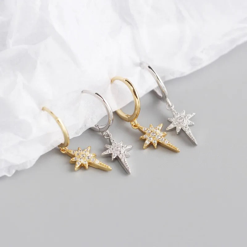 two pairs of silver and gold sparkly star hoop earrings. 