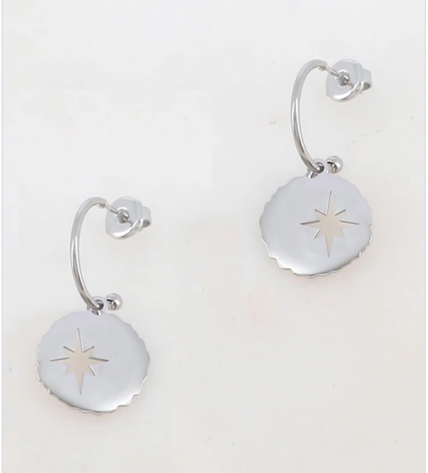 Pair of silver earrings with star designs on a light gray background