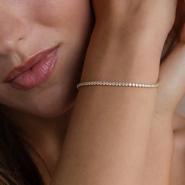 A close-up image of a woman's arm wearing a silver tennis bracelet with cubic zirconia crystals.