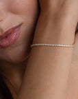 A close-up image of a woman's arm wearing a silver tennis bracelet with cubic zirconia crystals.