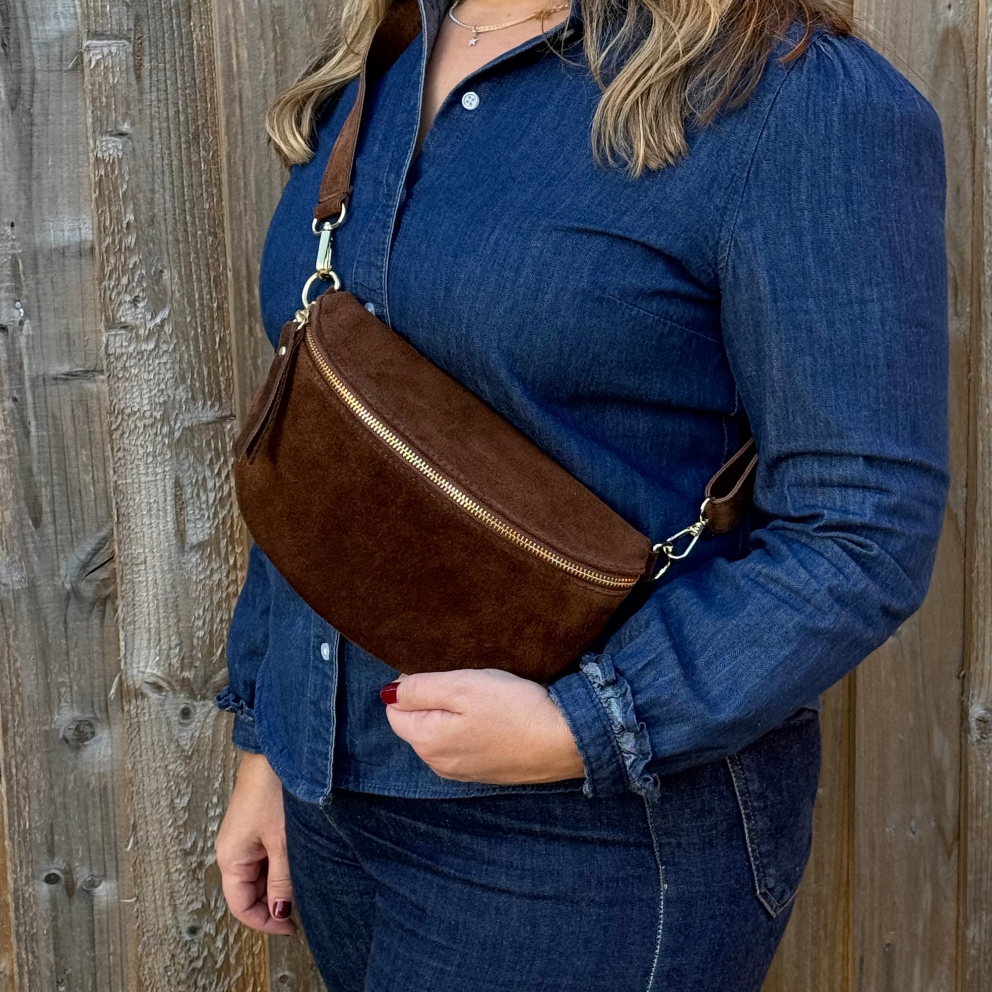 woman wearing a blue denim outfit with a brown suede bag  with gold accents