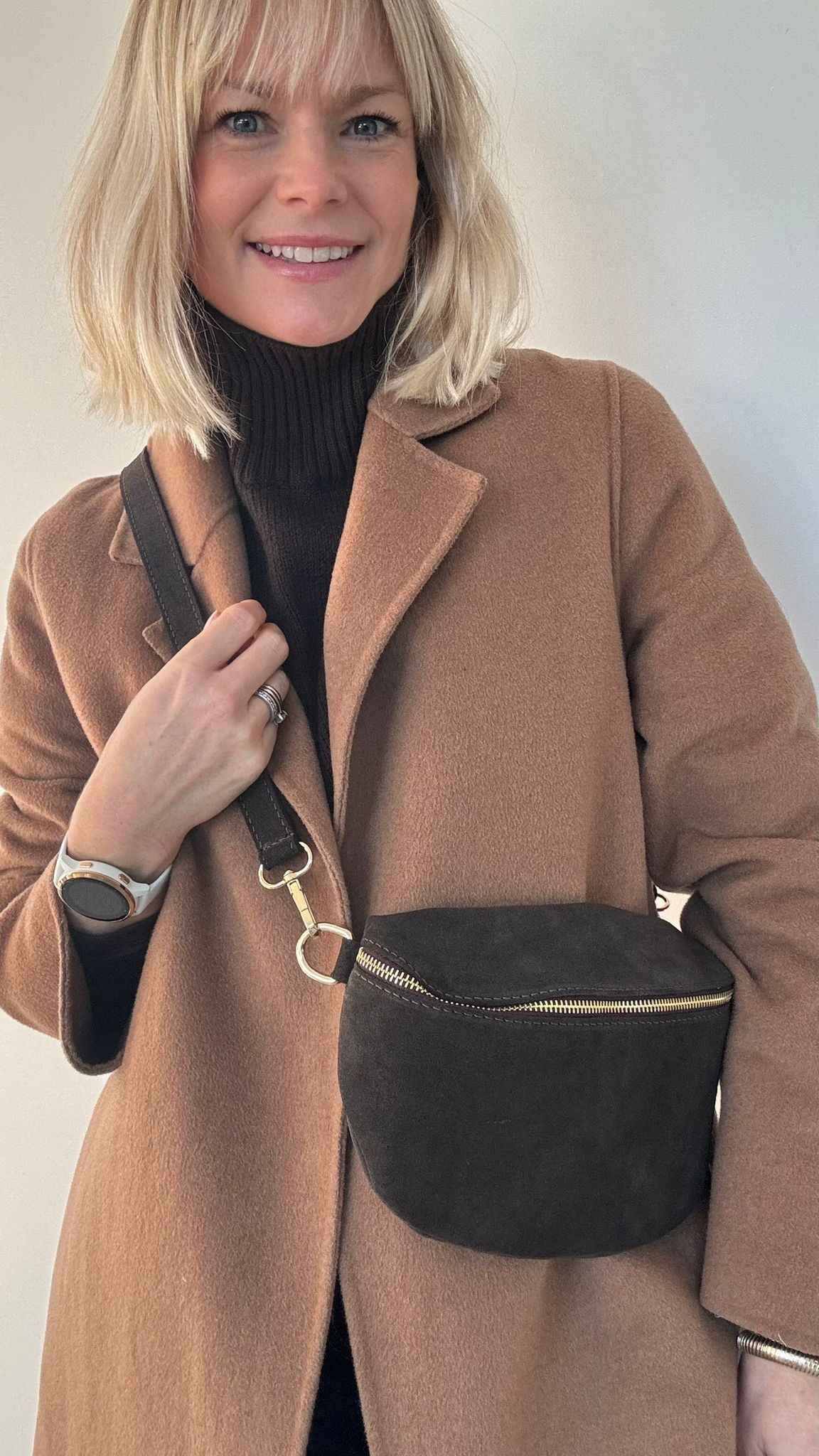 Woman wearing a brown coat with a dark brown crossbody/ waist bag