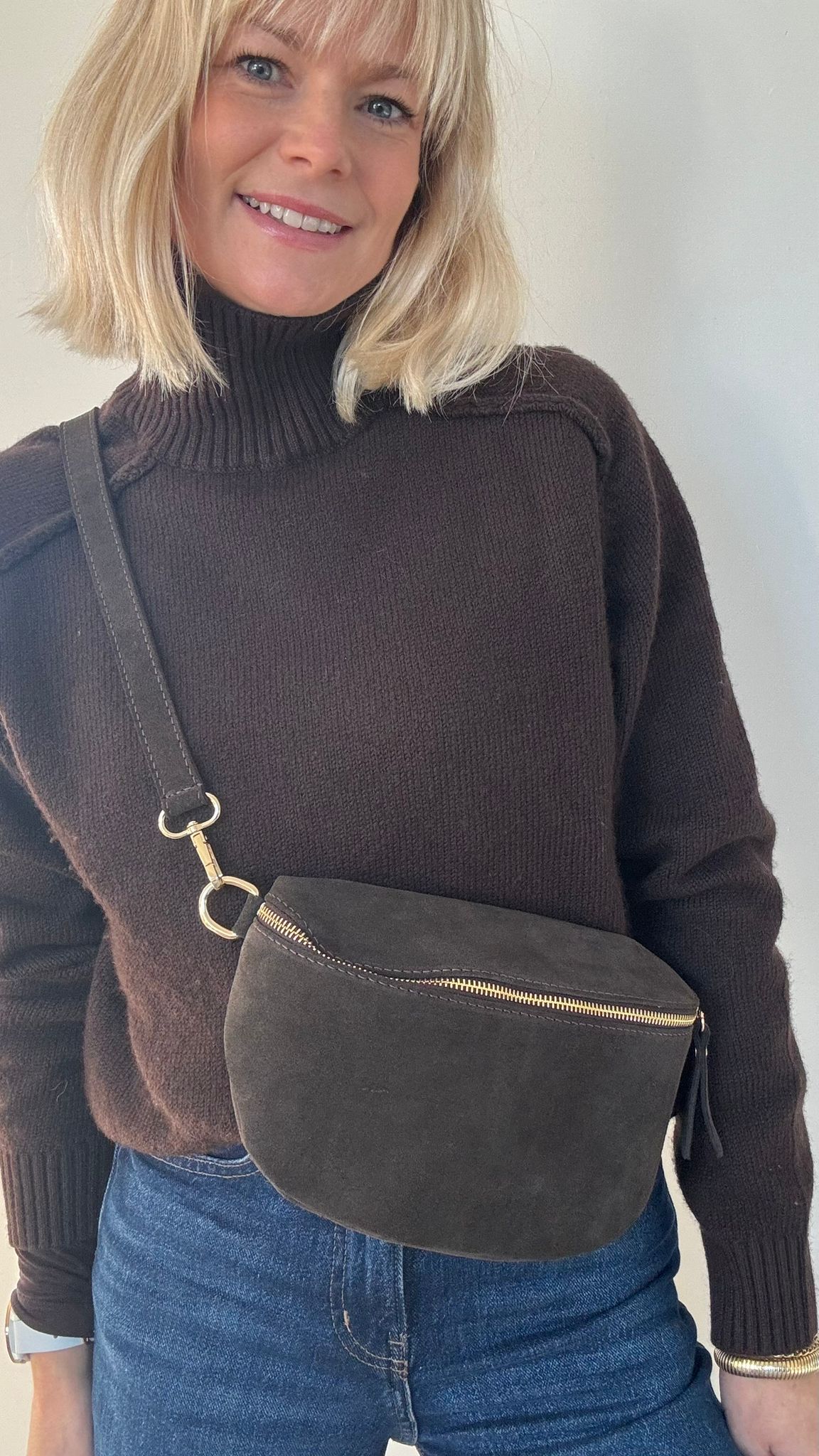 woman wearing a brown sweater with a dark brown leather crossbody bag 