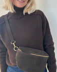 woman wearing a brown sweater with a dark brown leather crossbody bag 