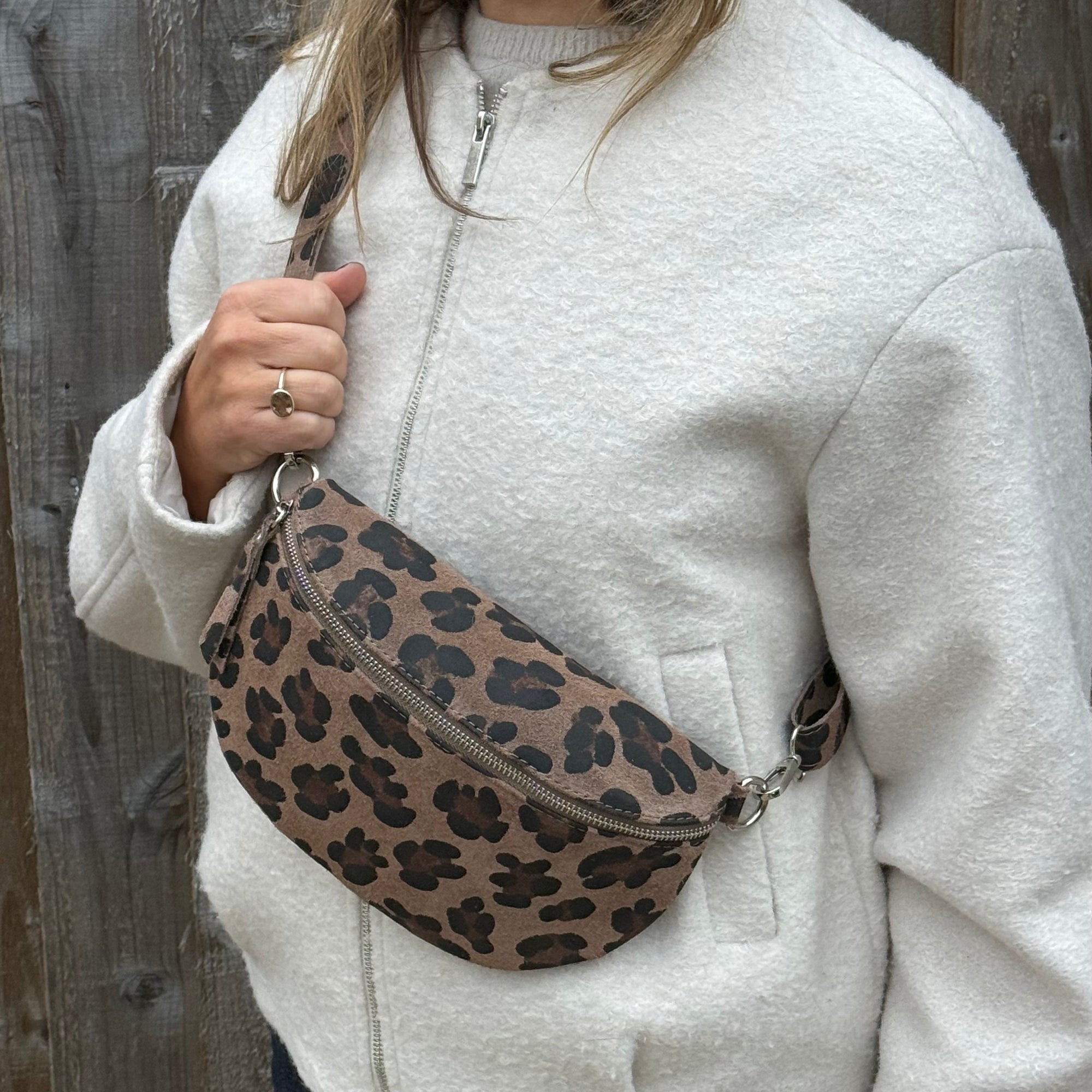 woman wearing a white jacket holding a large leopard print crossbody bag
