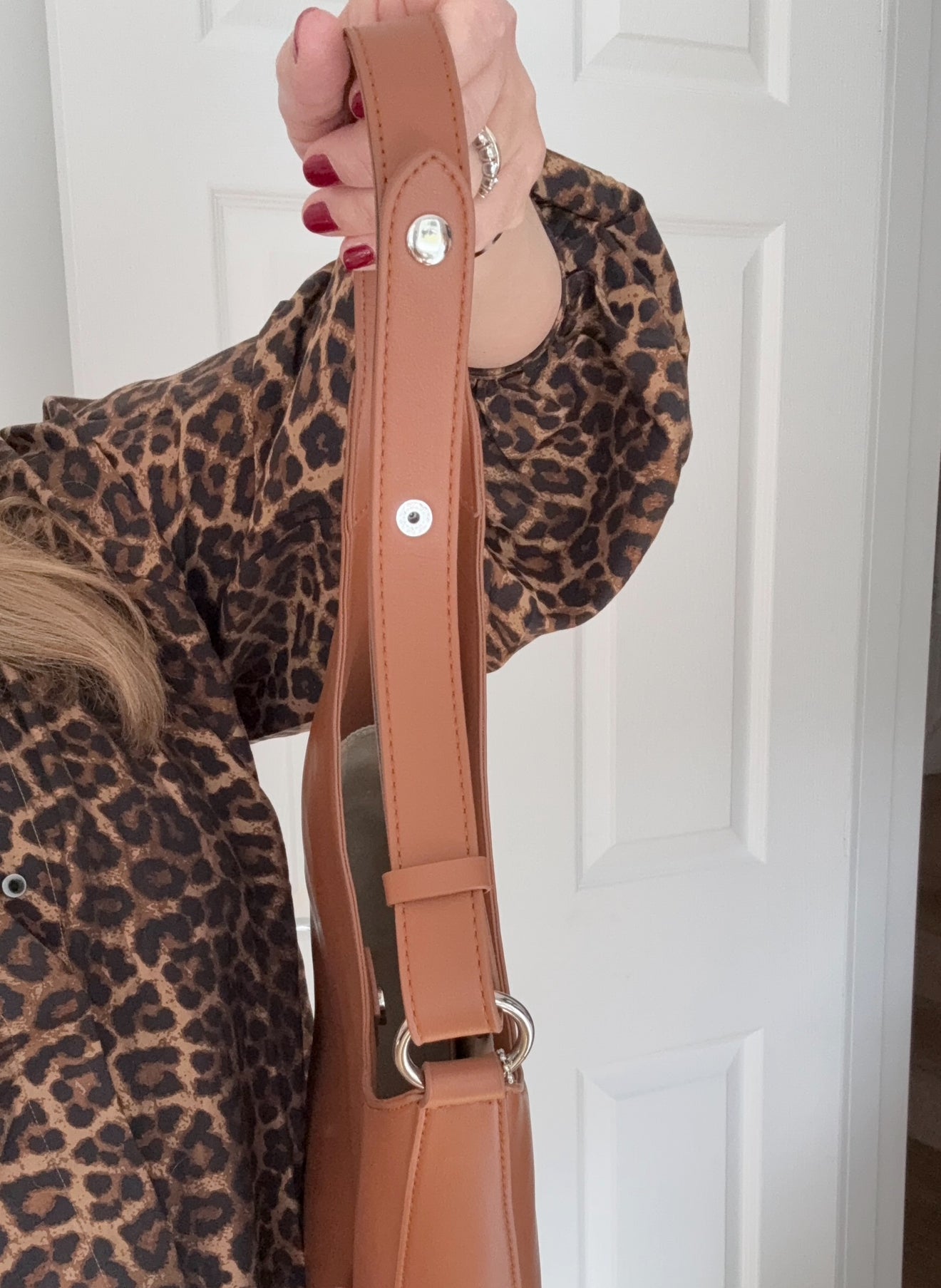 woman holding a brown shoulder strap with silver accents