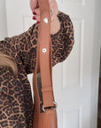 woman holding a brown shoulder strap with silver accents