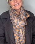 Woman wearing a mixed animal print scarf  over a black suede coat 