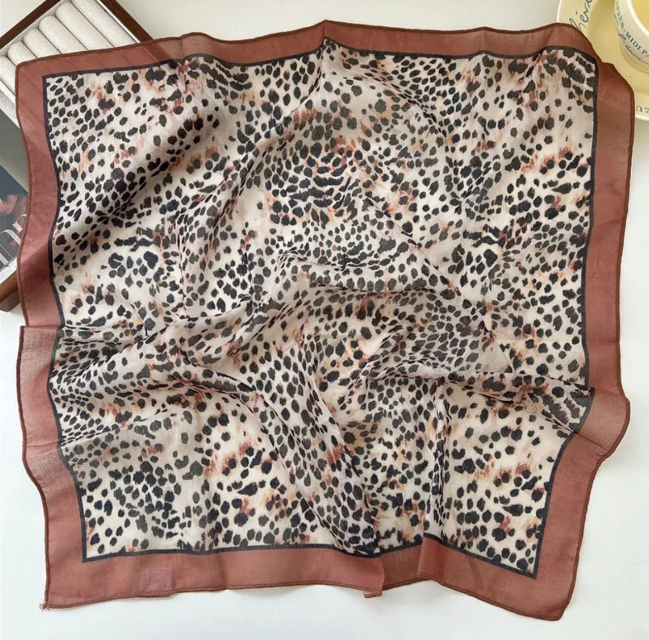 Animal print square scarf with brown border on a white background.
