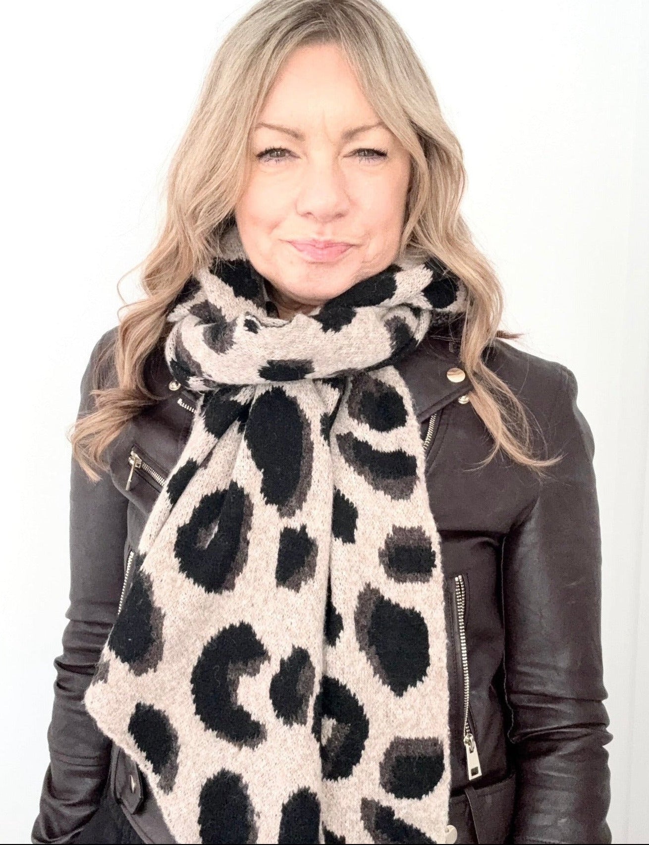 Woman wearing a leopard print scarf and black leather jacket on a white background