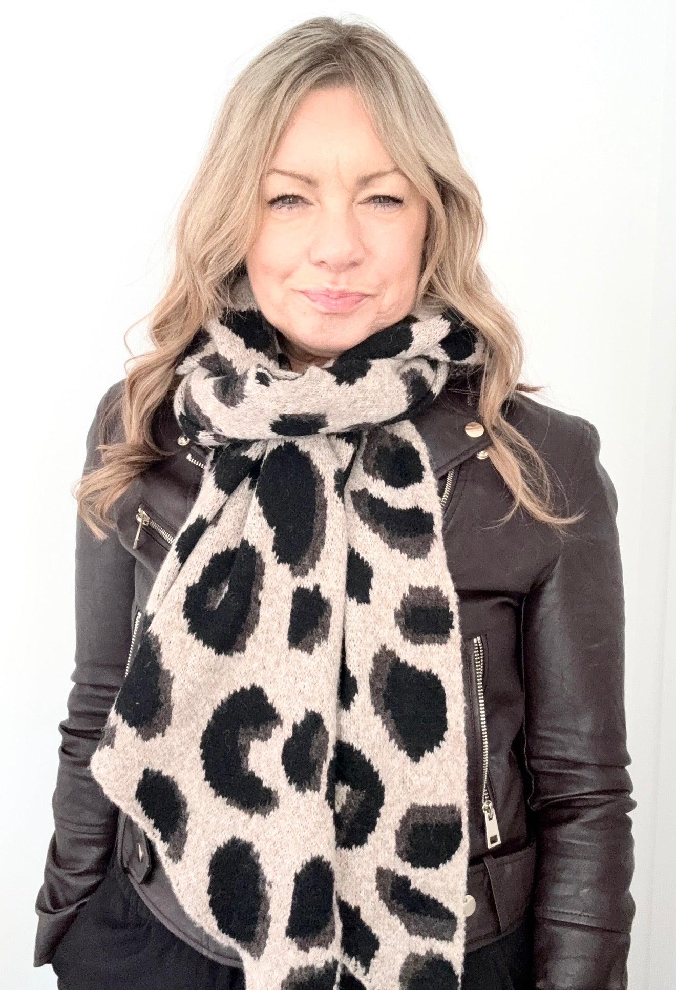 Woman wearing a leopard print scarf and black leather jacket on a white background