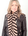 woman wearing a brwon leather jacket and a taupe and brown strped scarf