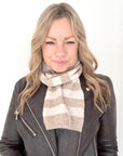 Woman wearing a taupe and cream knitted  striped scarf and leather jacket 