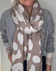 Woman wearing a large beige and white animal print scarf over a grey jumper