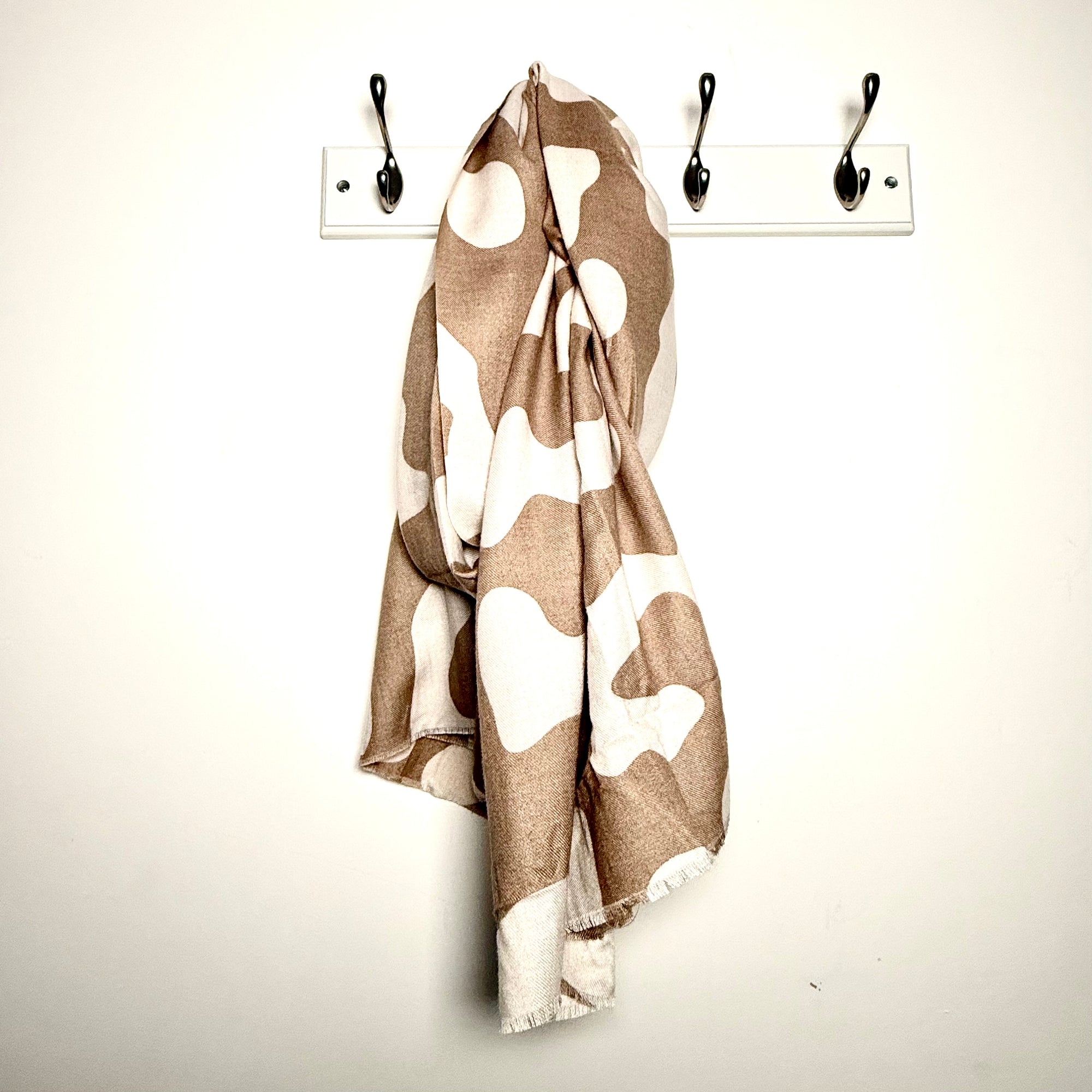 animal print patterned scarf draped over a peg on a white wall