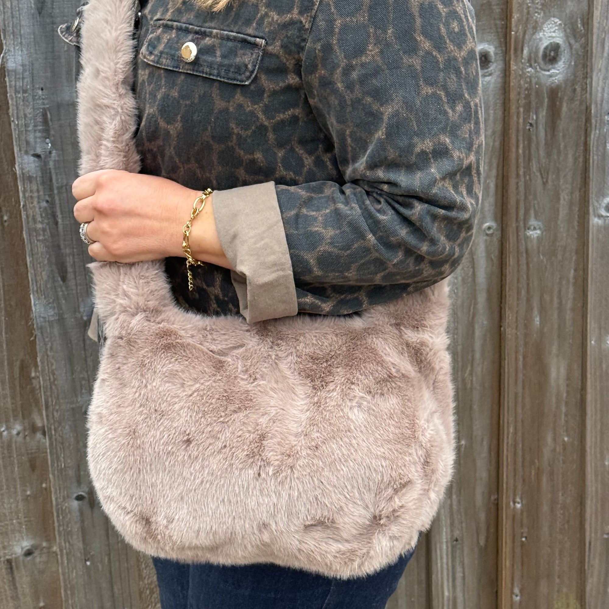 woman wearing a leopard print jacket with a fluffy beige bag against a wooden background