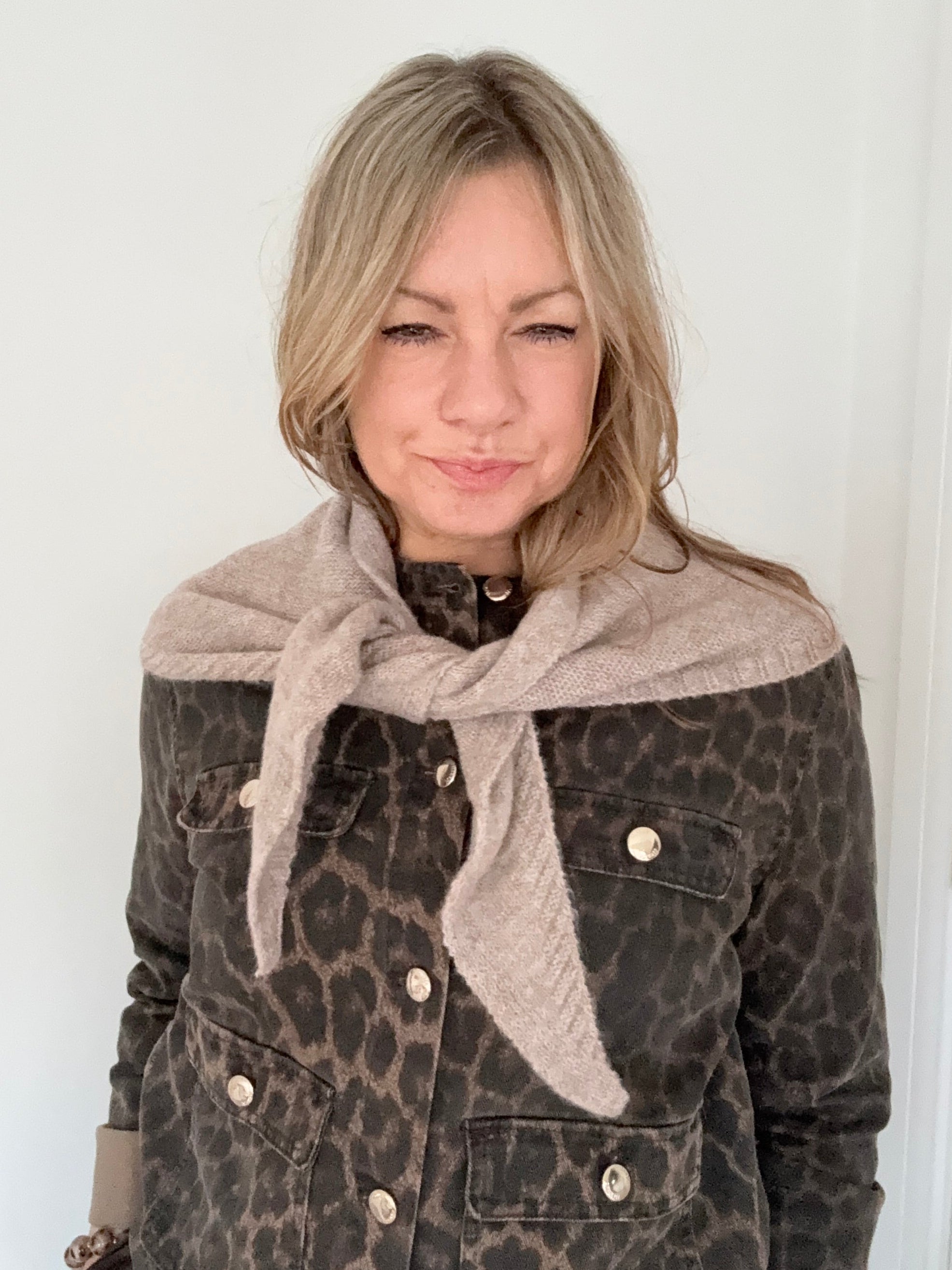Person wearing a leopard print jacket with a taupe triangle scarf
