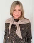 Person wearing a leopard print jacket with a taupe triangle scarf