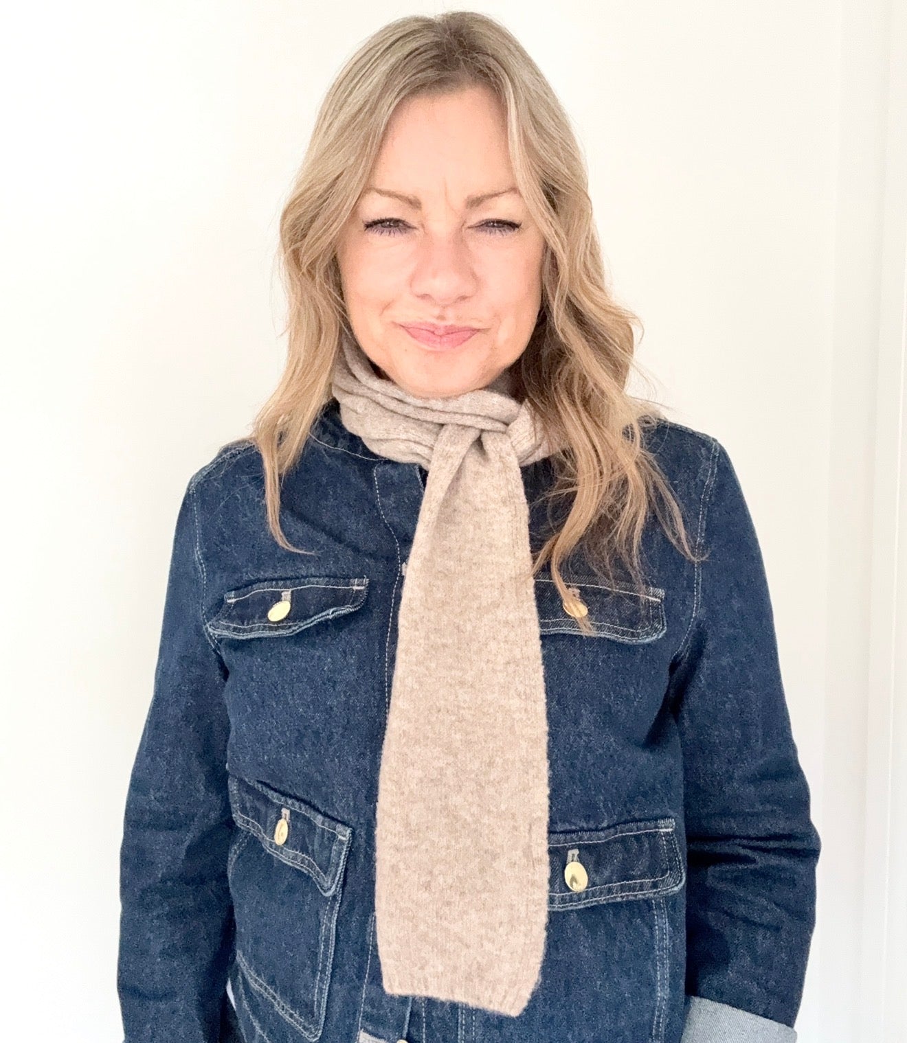 Woman wearing a denim jacket and taupe knitted narrow  scarf