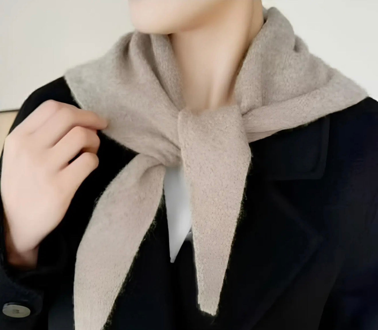Person wearing a beige scarf with a neutral background