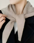 Person wearing a beige scarf with a neutral background