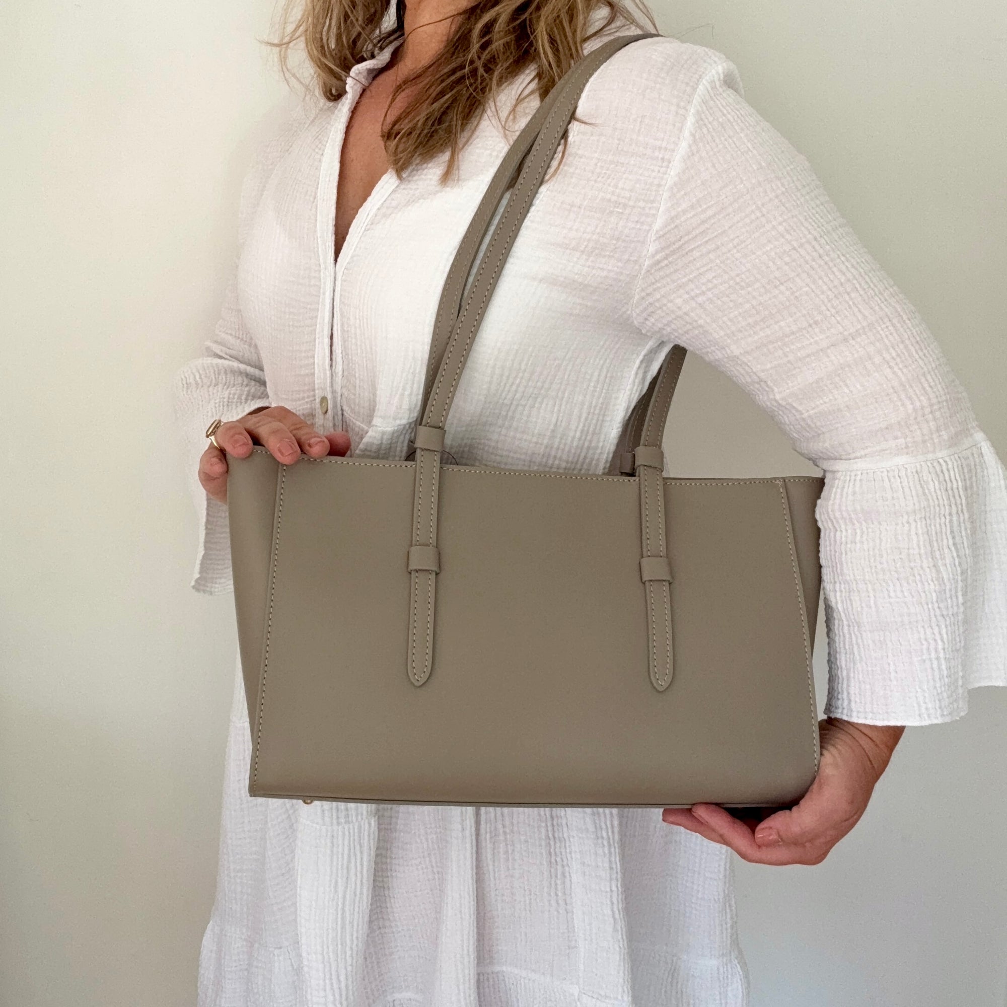 woman holding a beige leather tote handbag 