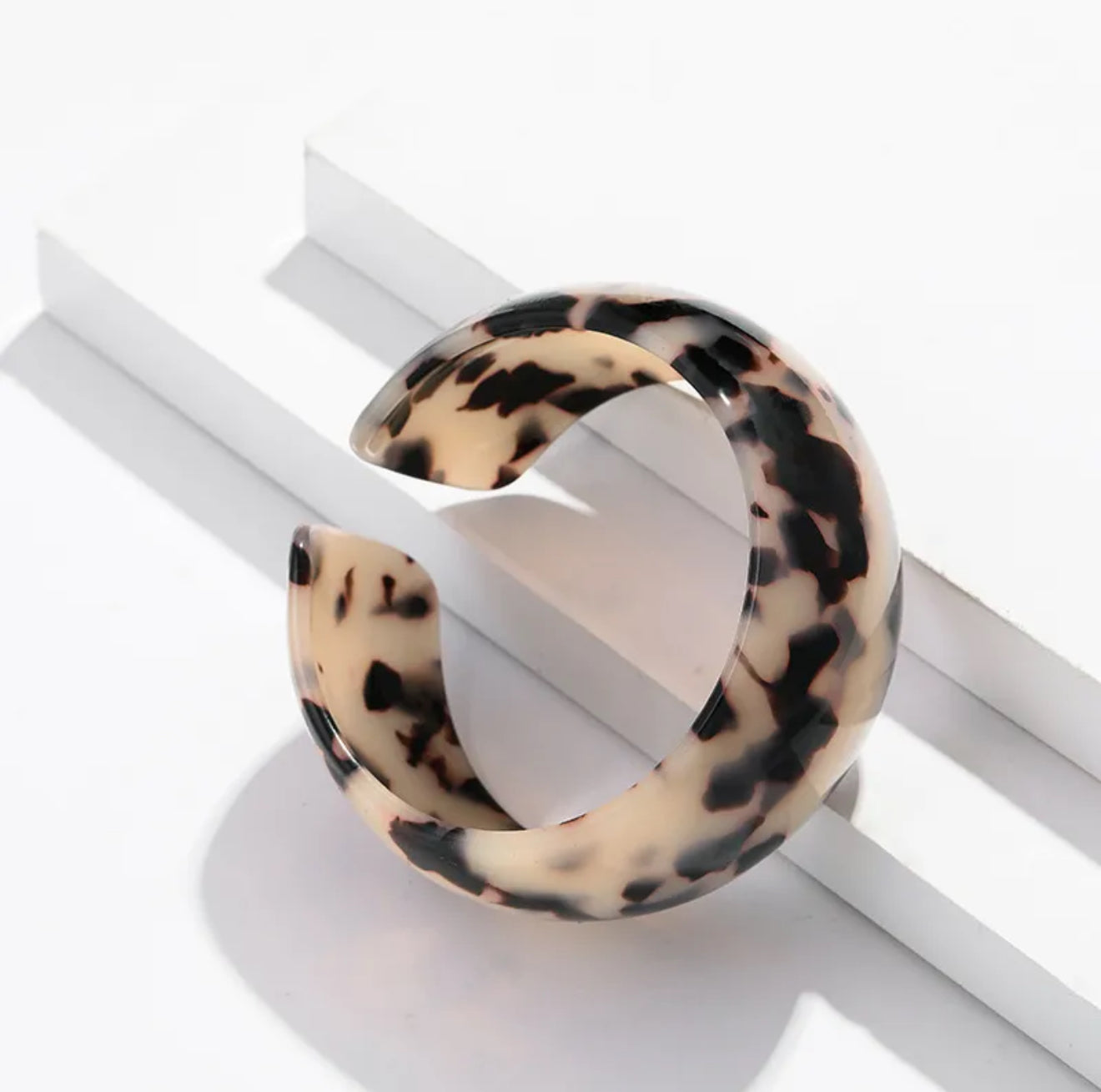 tortoiseshell print cuff bracelet on a white surface with a white background