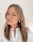 Woman wearing a white shirt with white flower earrings.