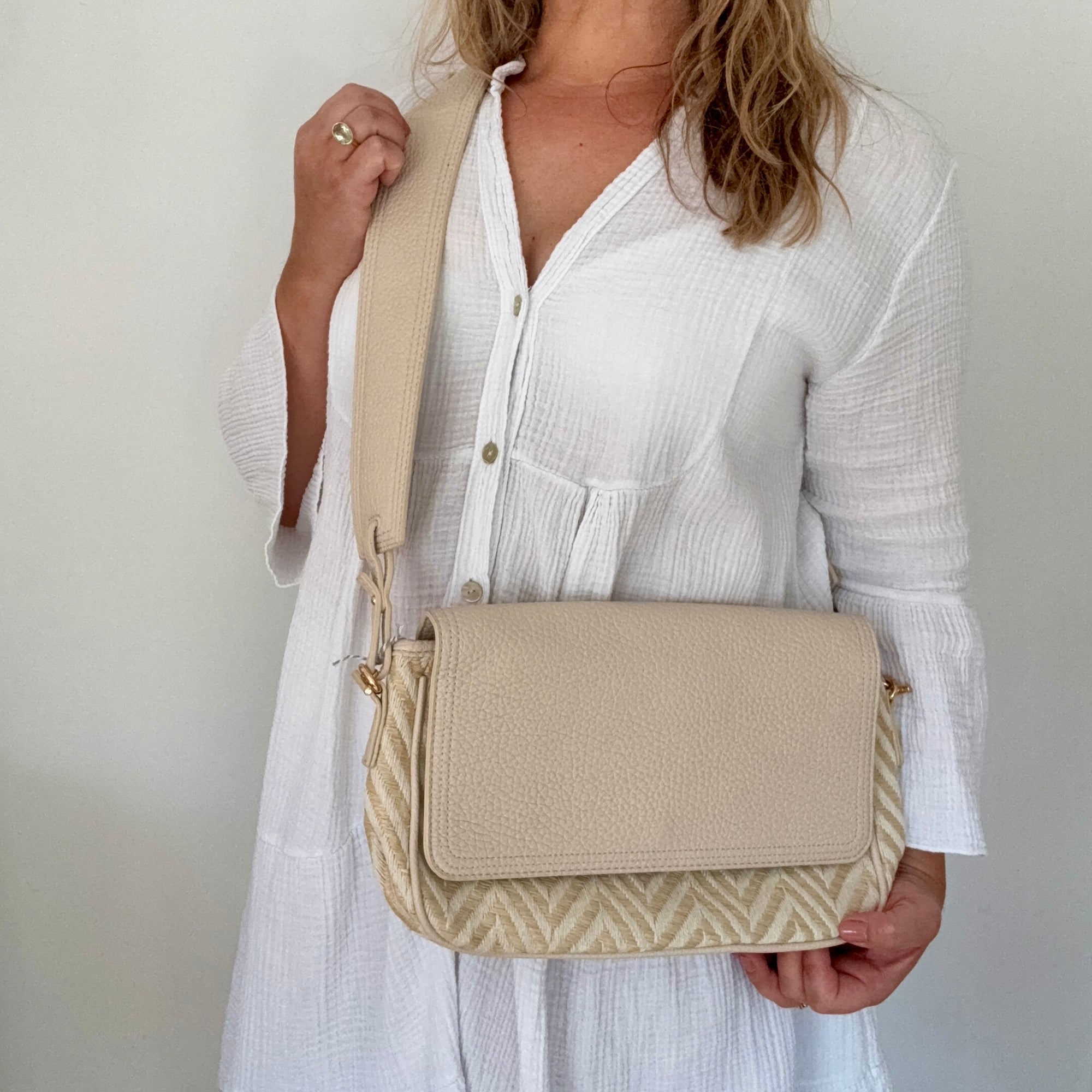 Woman holding a beige zig-zag crossbody bag 
